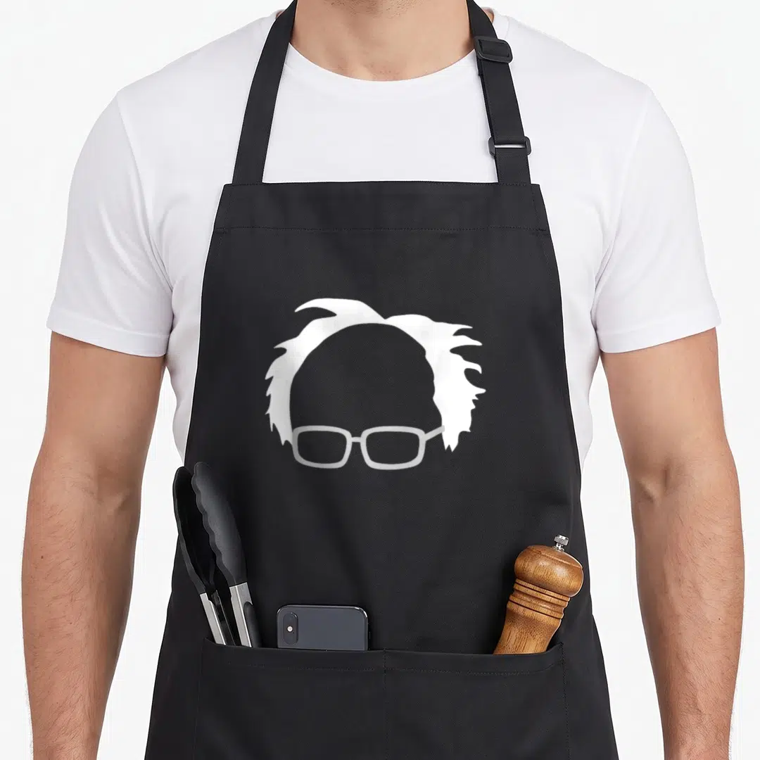 Bernie hair apron - Minimalist white messy hair and light grey glasses silhouette on grey background — shown on a black cotton canvas apron against a white background