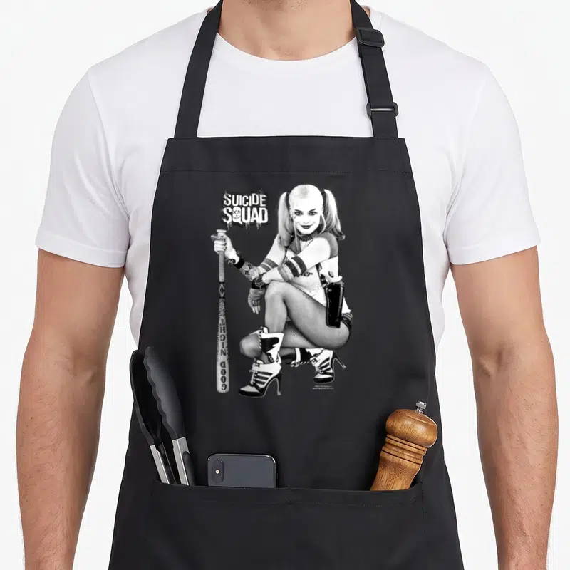 Kneel vehicle apron - Harley Quinn crouching with baseball bat and Suicide Squad text in black and white photo style — shown on a black cotton canvas apron against a white background