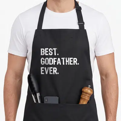 Funny godfather apron - White stacked text reading BEST. GODFATHER. EVER. on grey background — shown on a black cotton canvas apron against a white background
