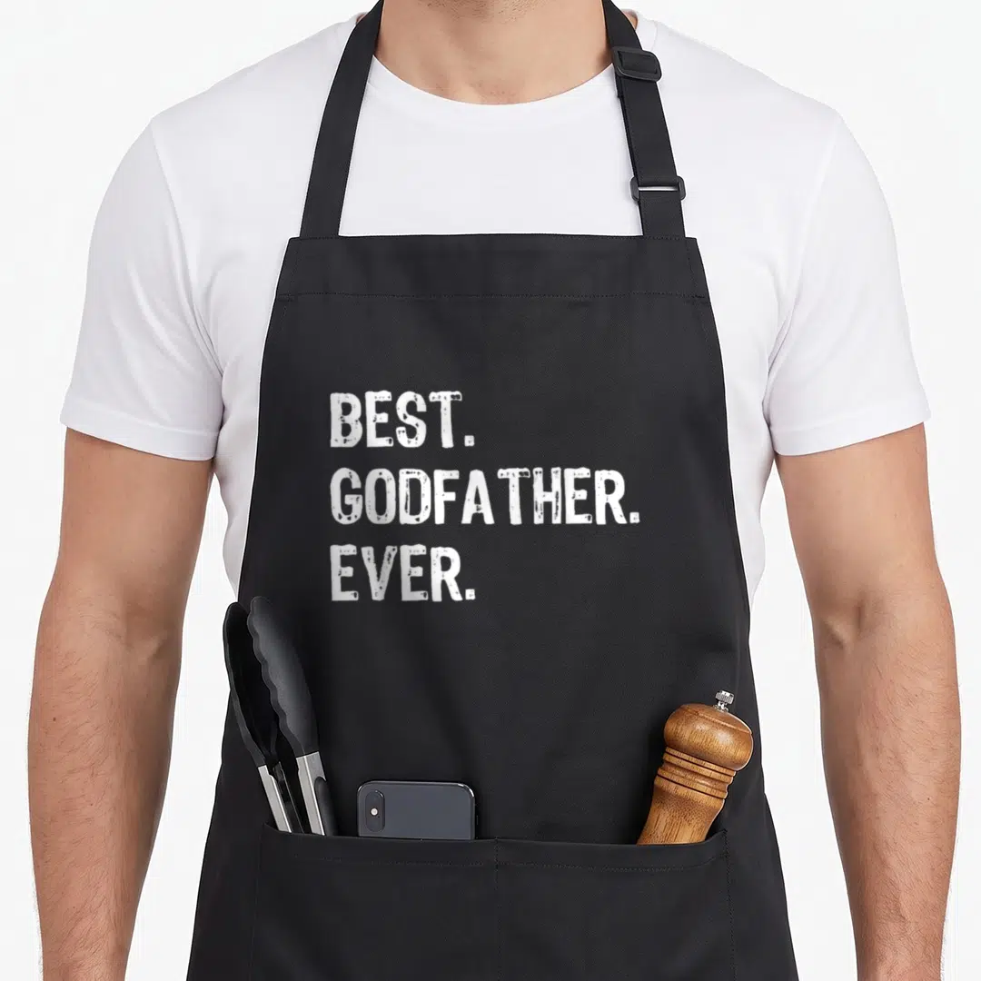 Funny godfather apron - White stacked text reading BEST. GODFATHER. EVER. on grey background — shown on a black cotton canvas apron against a white background