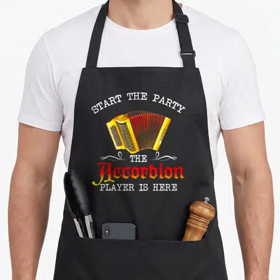 Start accordion apron - Yellow and red cartoon accordion with arched white text and decorative swirls — shown on a black cotton canvas apron against a white background