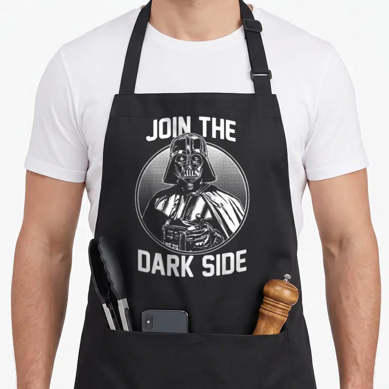 Join collegiate aprons - White retro Darth Vader in circle with text JOIN THE DARK SIDE — shown on a black cotton canvas apron against a white background
