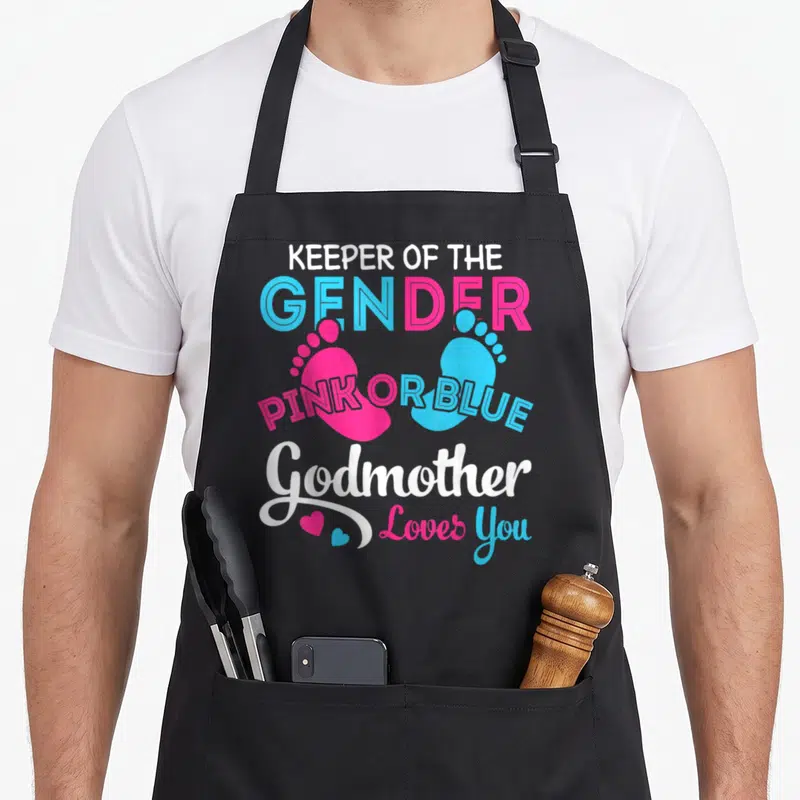 Godmother apron or apron - Pink and blue baby footprints with gender reveal text and hearts — shown on a black cotton canvas apron against a white background