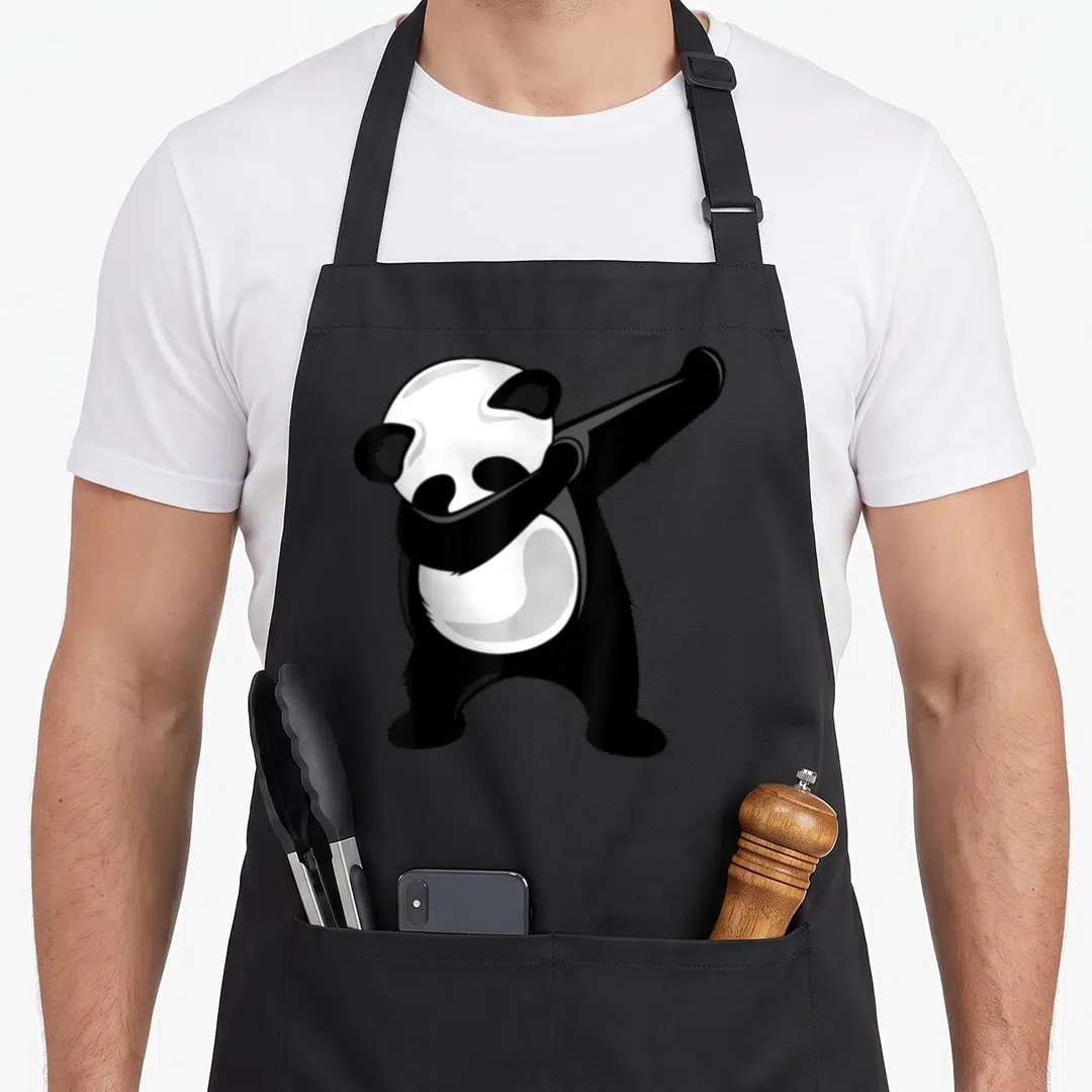 Dabbing bear apron - Cartoon panda performing a dab pose in black and white — shown on a black cotton canvas apron against a white background