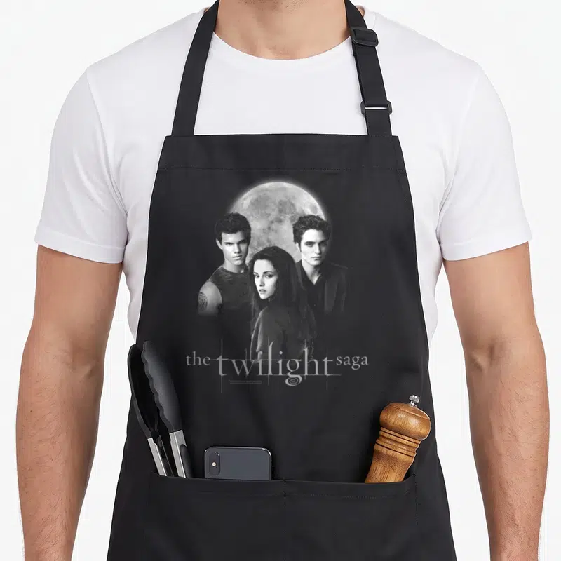 Jacob edwards aprons - Grey and white photo of three people and a moon with the twilight saga text at the bottom — shown on a black cotton canvas apron against a white background