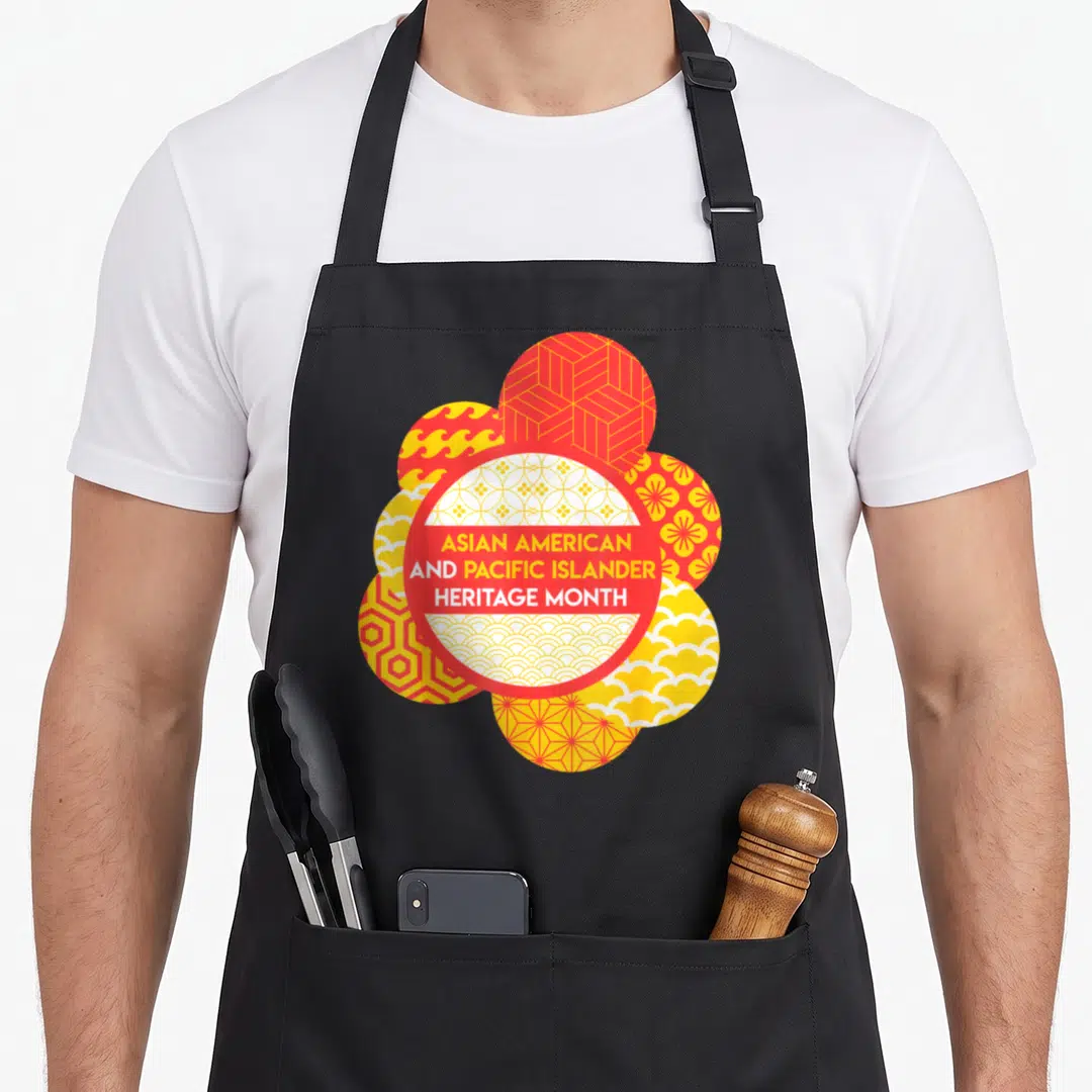 Pacific asian apron - Red and yellow patterned circles with ASIAN AMERICAN AND PACIFIC ISLANDER HERITAGE MONTH text — shown on a black cotton canvas apron against a white background