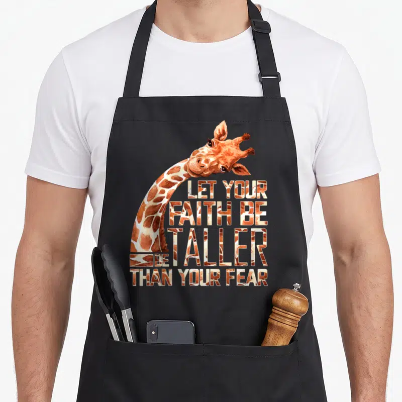 Faith giraffe apron - Watercolor giraffe neck curving around four lines of text filled with hide pattern — shown on a black cotton canvas apron against a white background