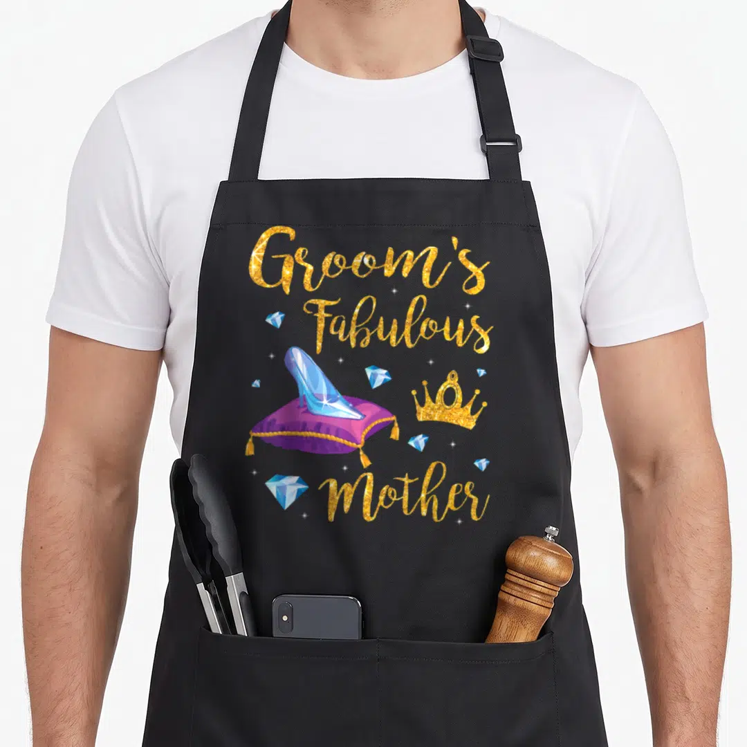 Memory wedding day aprons - Groom's Fabulous Mother gold text with blue glass slipper on purple pillow and crown — shown on a black cotton canvas apron against a white background