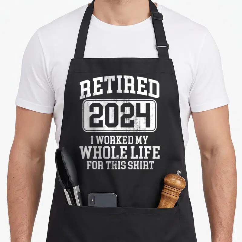 Funny retired retirement apron - White distressed text reading RETIRED 2024 I worked my whole life for this shirt — shown on a black cotton canvas apron against a white background