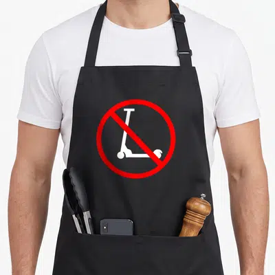 Skater scooter apron - White scooter silhouette inside red circle with diagonal slash — shown on a black cotton canvas apron against a white background