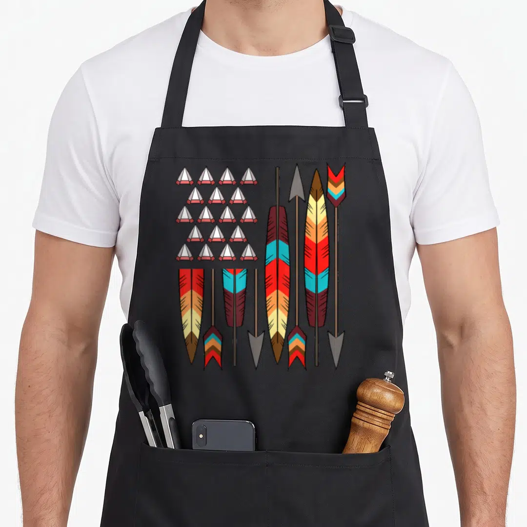Native pride american flag apron - Cartoon arrows in red, yellow, blue, brown, and grey arranged in a flag formation — shown on a black cotton canvas apron against a white background