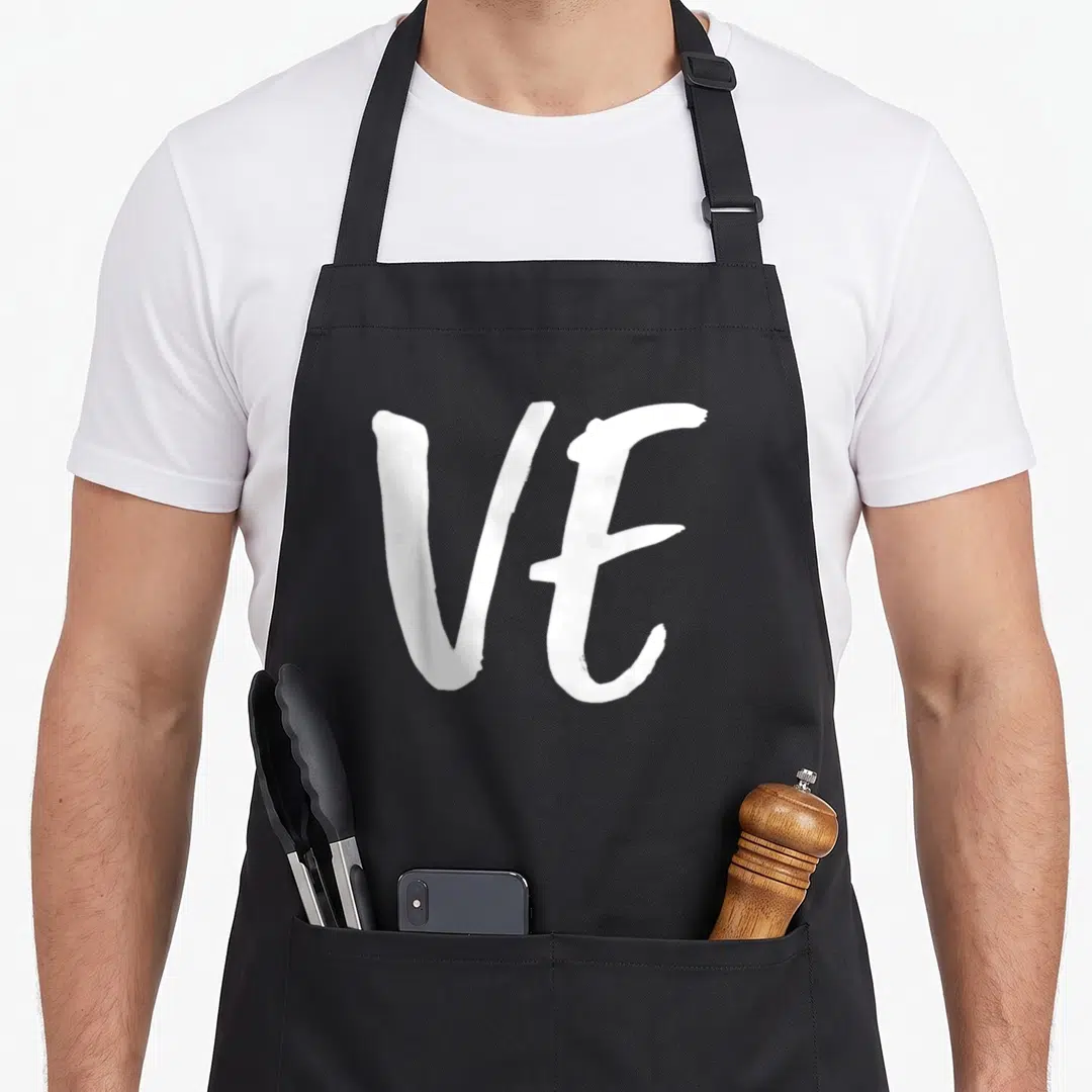 Couple valentine apron - White brush-style VE letters on a black background — shown on a black cotton canvas apron against a white background