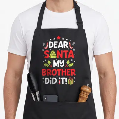 Brother christmas santa apron - Stacked text DEAR SANTA MY BROTHER DID IT! with red star, candy canes, holly — shown on a black cotton canvas apron against a white background