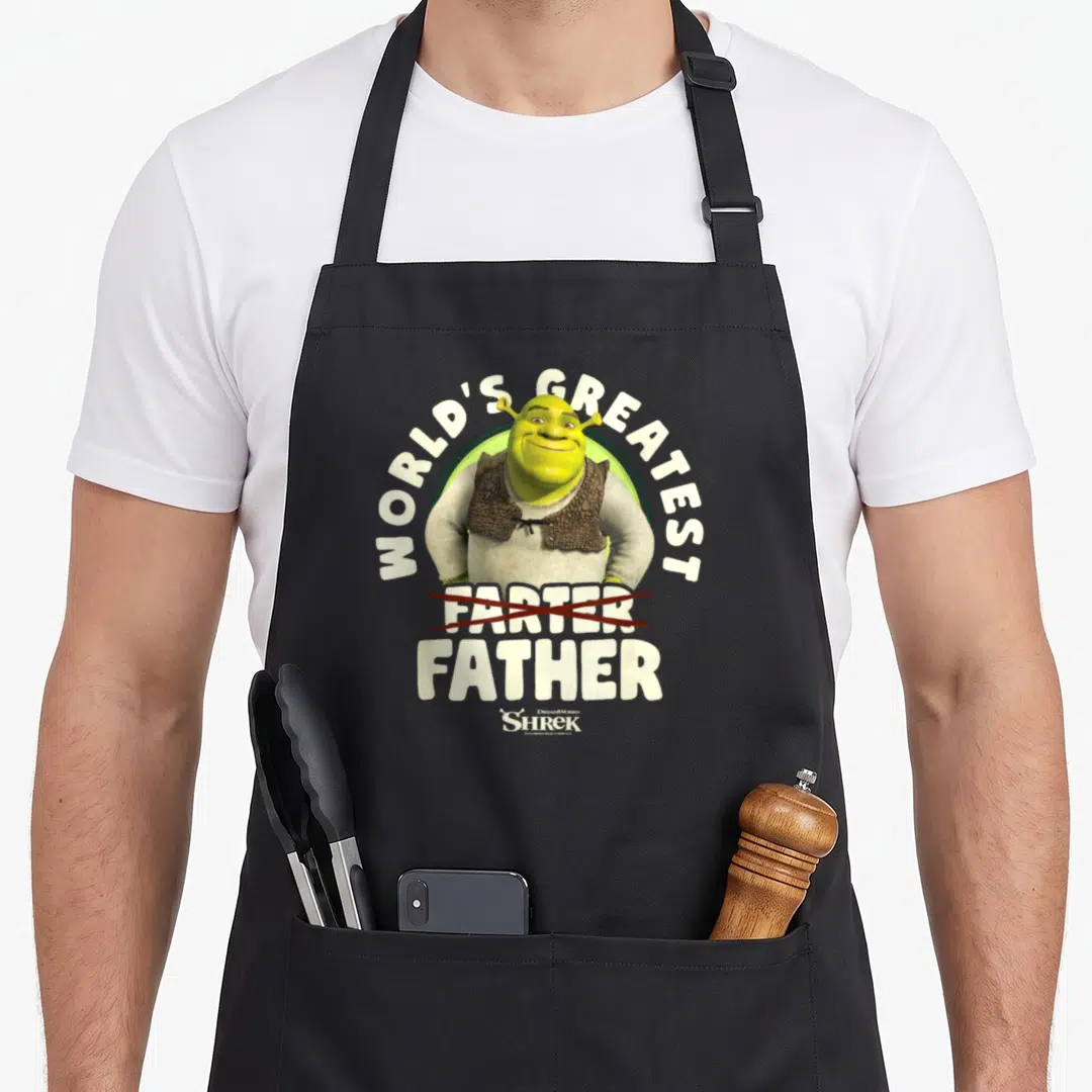 Crossed worlds greatest dad apron - Shrek illustration with crossed out Farter and printed Father text in green — shown on a black cotton canvas apron against a white background
