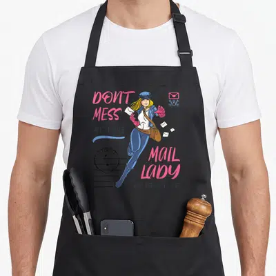 Mess postal aprons - Cartoon mail lady with pink text, stamp, and postmark on grey background — shown on a black cotton canvas apron against a white background