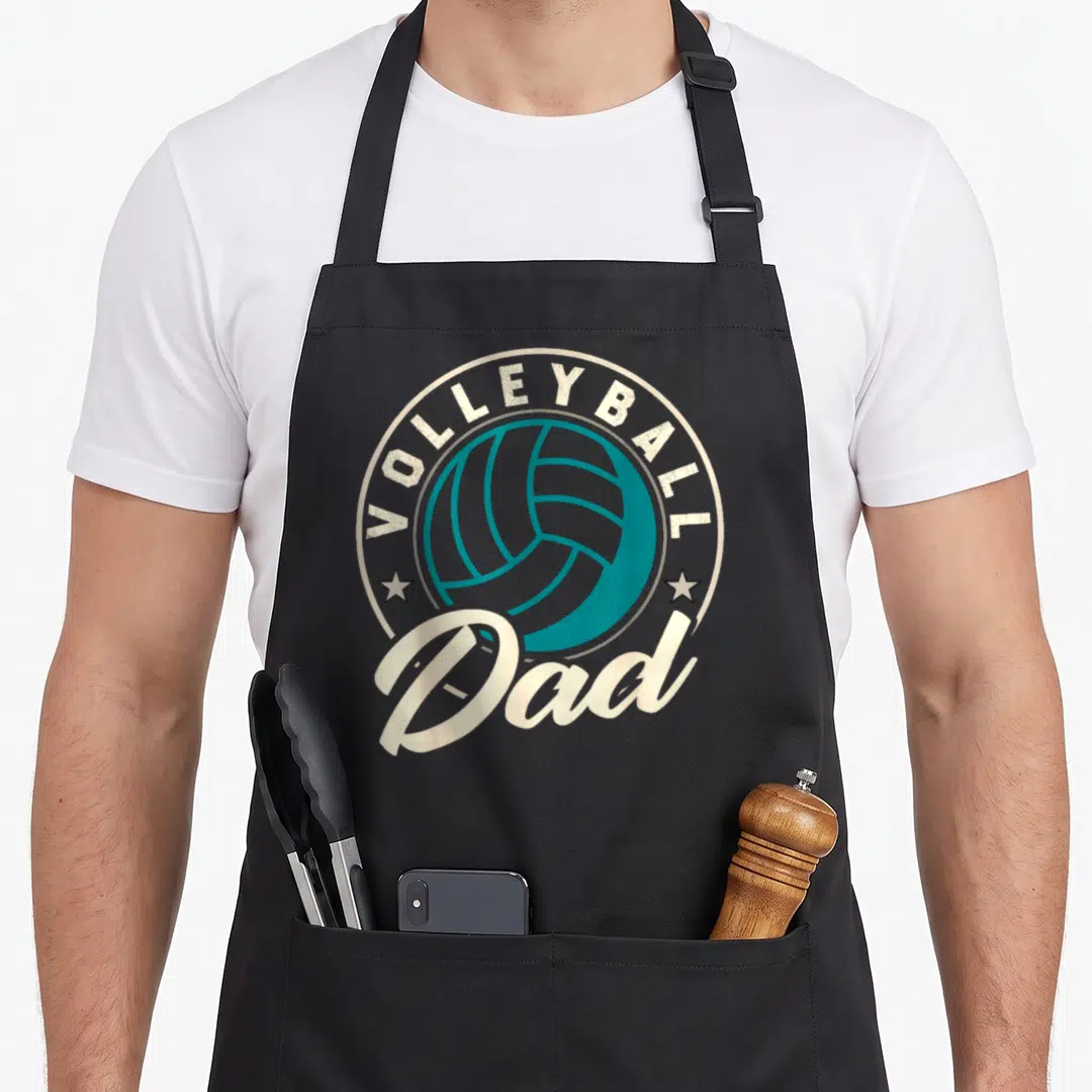 Beach sports dad apron - Teal volleyball inside cream circle with VOLLEYBALL Dad text and two stars — shown on a black cotton canvas apron against a white background