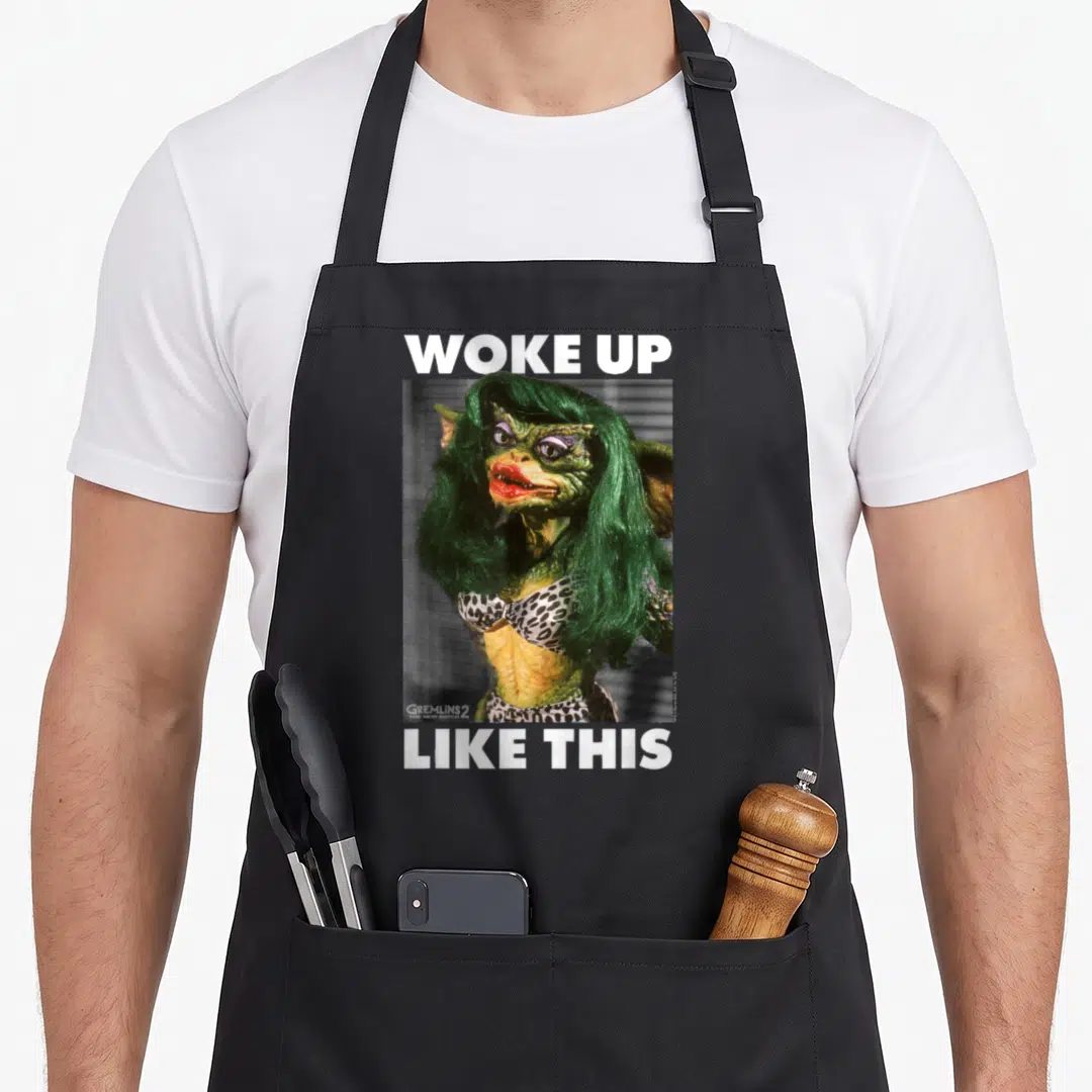 Monster morning apron - Woke Up Like This text framing female Gremlin in leopard bikini photo — shown on a black cotton canvas apron against a white background
