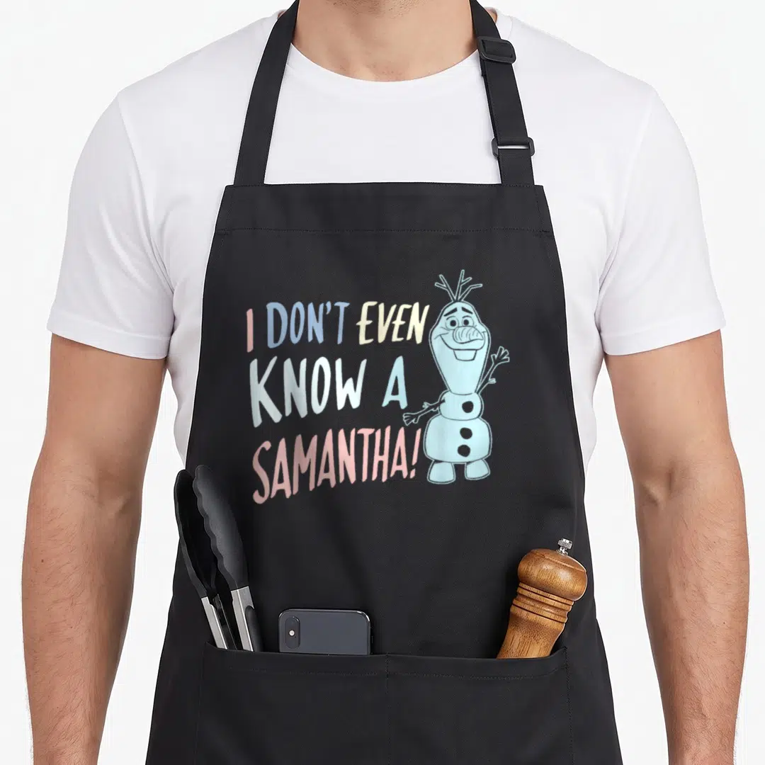 Even frozen apron - Stacked text I DON'T EVEN KNOW A SAMANTHA next to standing snowman in pastel colors — shown on a black cotton canvas apron against a white background