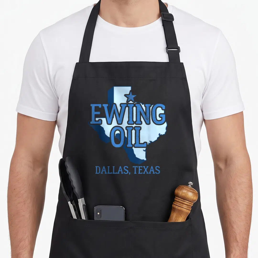 Ewing texas apron - Blue Texas map with Ewing Oil text and Dallas label — shown on a black cotton canvas apron against a white background