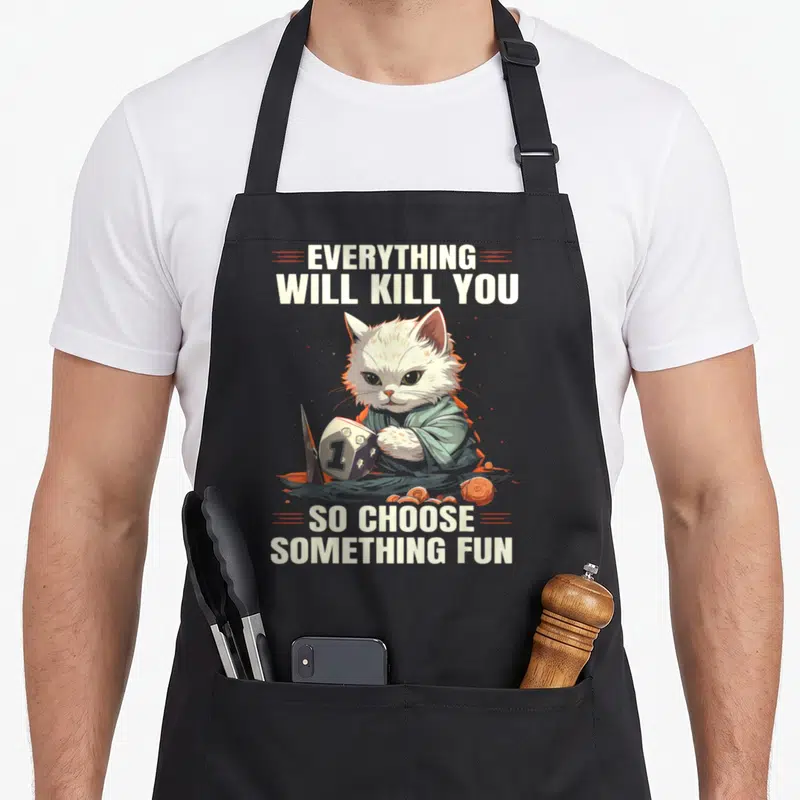 D20 gaming apron - Cartoon cat holding d20 die with knife and coins under sarcastic text — shown on a black cotton canvas apron against a white background