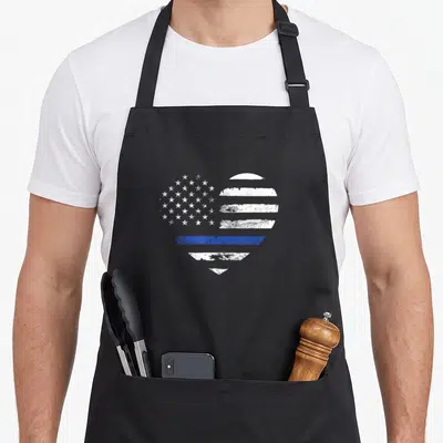 Blue line apron - Distressed heart shape filled with white stars and stripes and one horizontal blue line — shown on a black cotton canvas apron against a white background