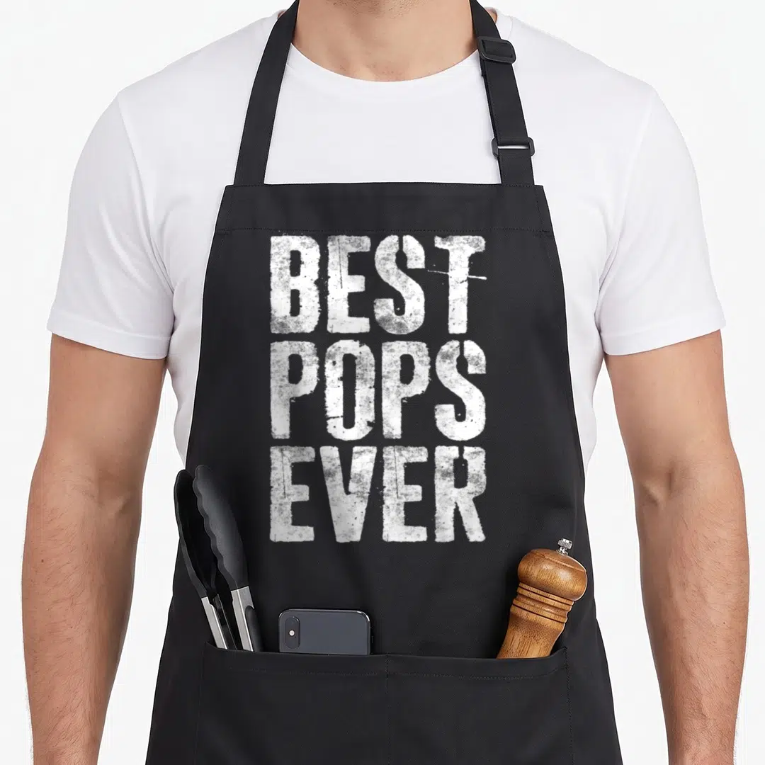 Grandfather father day apron - White distressed text reading BEST POPS EVER stacked vertically on black fabric — shown on a black cotton canvas apron against a white background