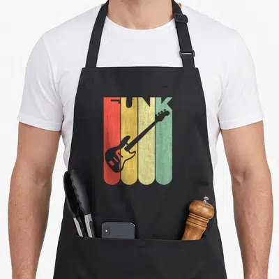 Loving funk apron - Grey electric guitar over four vertical stripes red orange yellow green with FUNK text — shown on a black cotton canvas apron against a white background