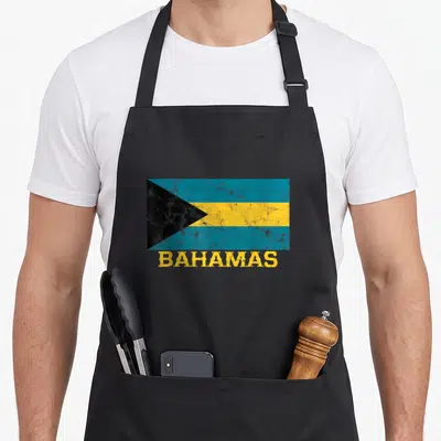 Bahamian pride apron - Distressed flag of Bahamas in blue yellow black with BAHAMAS text below — shown on a black cotton canvas apron against a white background