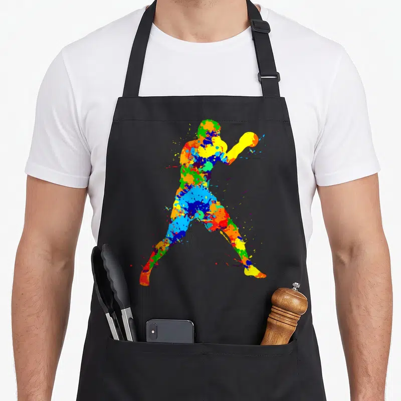 Boxing boxer apron - Multicolored watercolor paint splatter silhouette of an athlete holding a ball — shown on a black cotton canvas apron against a white background