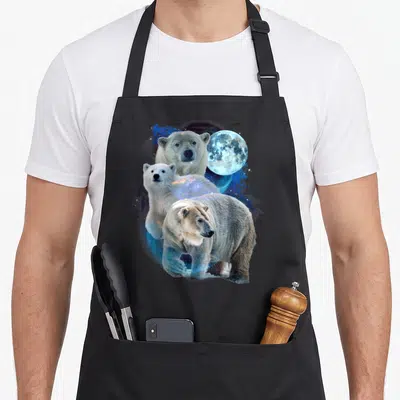 Moon bear apron - Three polar bears layered with a blue moon and cosmic splashes on black fabric — shown on a black cotton canvas apron against a white background