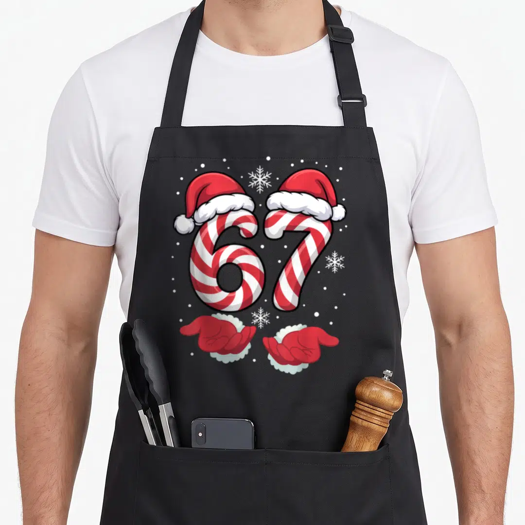 Xmas viral candy cane apron - Red and white 67 candy canes with Santa hats and gloved hands surrounded by snowflakes — shown on a black cotton canvas apron against a white background