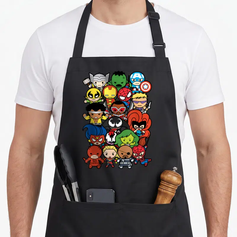 Heroe villain kawaii apron - Chibi superhero cluster in vertical oval with red blue yellow green black cartoon figures — shown on a black cotton canvas apron against a white background