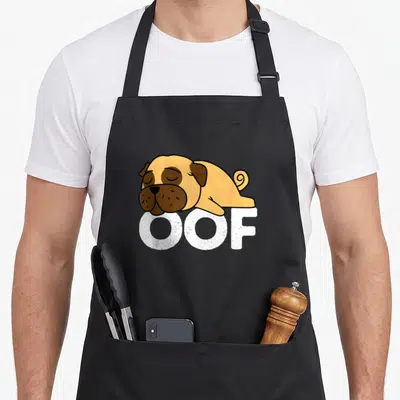 Pug gaming apron - Sleeping cartoon pug lying on white OOF text in tan and black — shown on a black cotton canvas apron against a white background