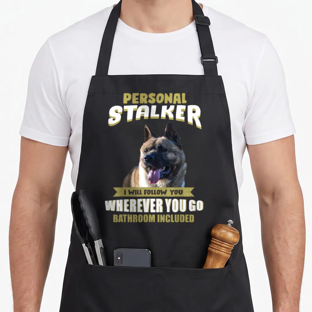 Funny akita apron - Photo of brown and white dog with Personal Stalker text and gold ribbon banner — shown on a black cotton canvas apron against a white background