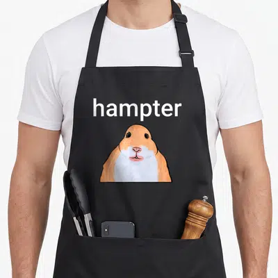 Hampter meme apron - Cartoon hamster in orange and white with hampter text above head — shown on a black cotton canvas apron against a white background