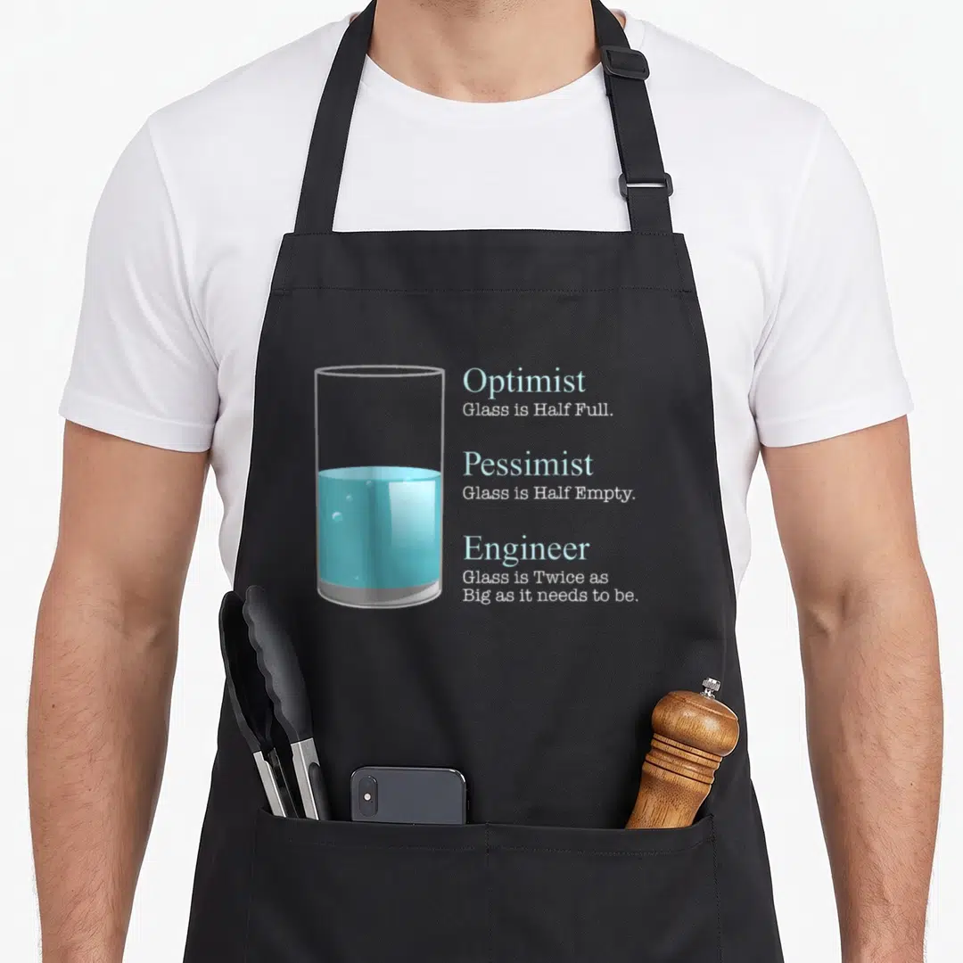 Engineering mechanical engineer apron - Minimalist glass of blue water next to stacked text about optimist pessimist — shown on a black cotton canvas apron against a white background