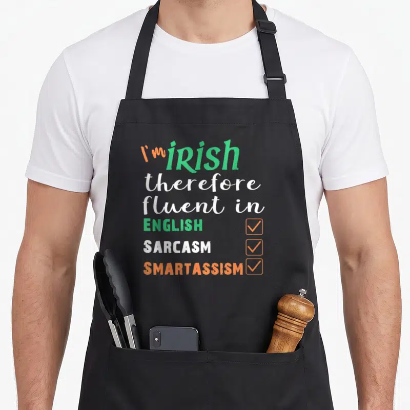 Irish smart apron - Stacked text I'm Irish fluent in English sarcasm smartassism with three checked boxes in green — shown on a black cotton canvas apron against a white background