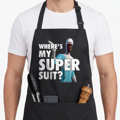 Frozone novelty apron - Stacked white text WHERE'S MY SUPER SUIT beside blue grey cartoon character pointing finger — shown on a black cotton canvas apron against a white background