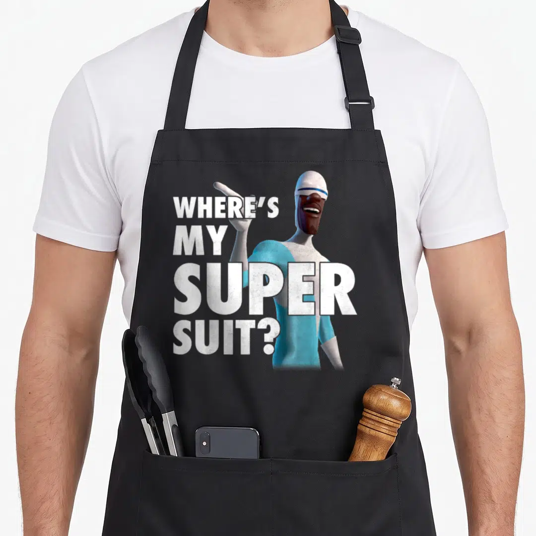 Frozone novelty apron - Stacked white text WHERE'S MY SUPER SUIT beside blue grey cartoon character pointing finger — shown on a black cotton canvas apron against a white background