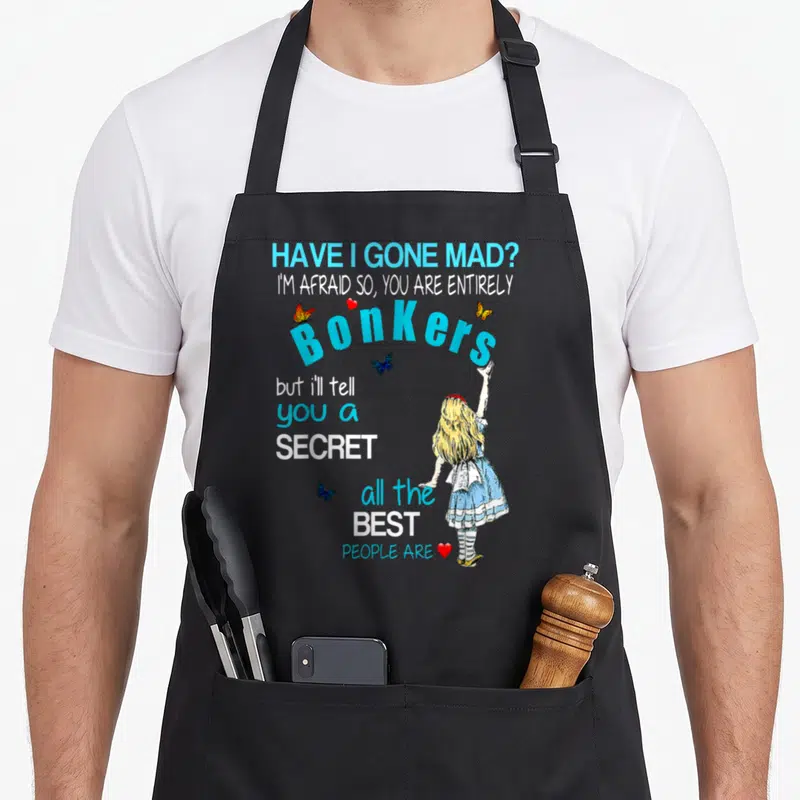 Gone alice wonderland apron - Stacked quote with girl standing right, blue text, butterflies, hearts, cartoon style — shown on a black cotton canvas apron against a white background