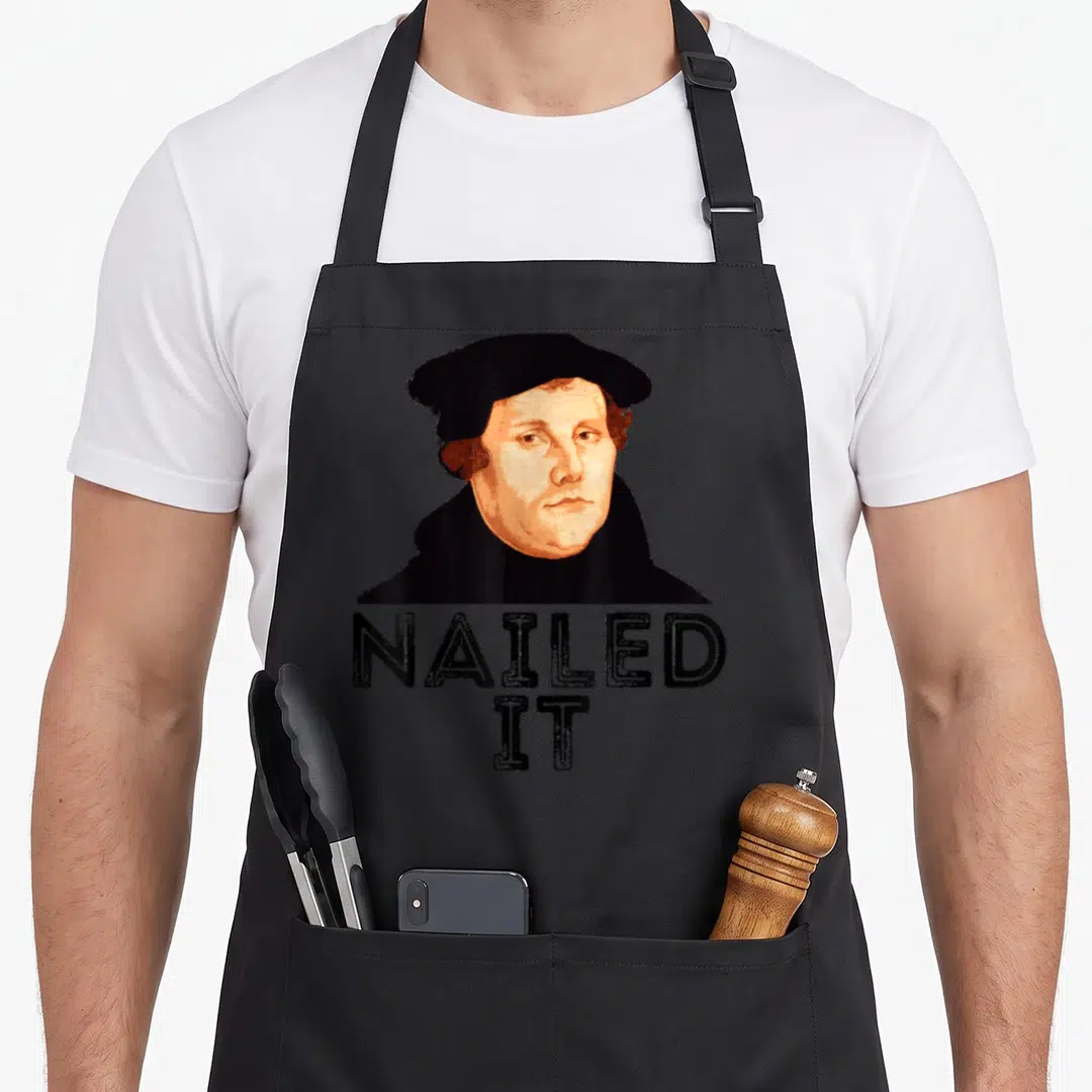 Luther nailed it aprons - Retro portrait of Martin Luther above stacked NAILED IT text in black and peach — shown on a black cotton canvas apron against a white background