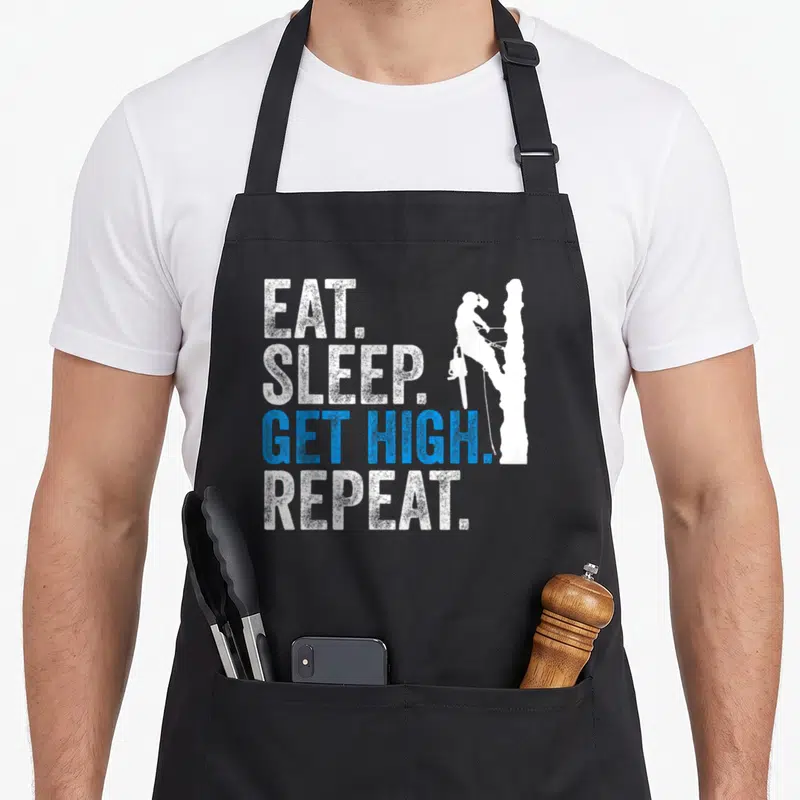 Eat dad mode apron - Stacked text EAT SLEEP GET HIGH REPEAT next to a tree climber silhouette in white and blue — shown on a black cotton canvas apron against a white background