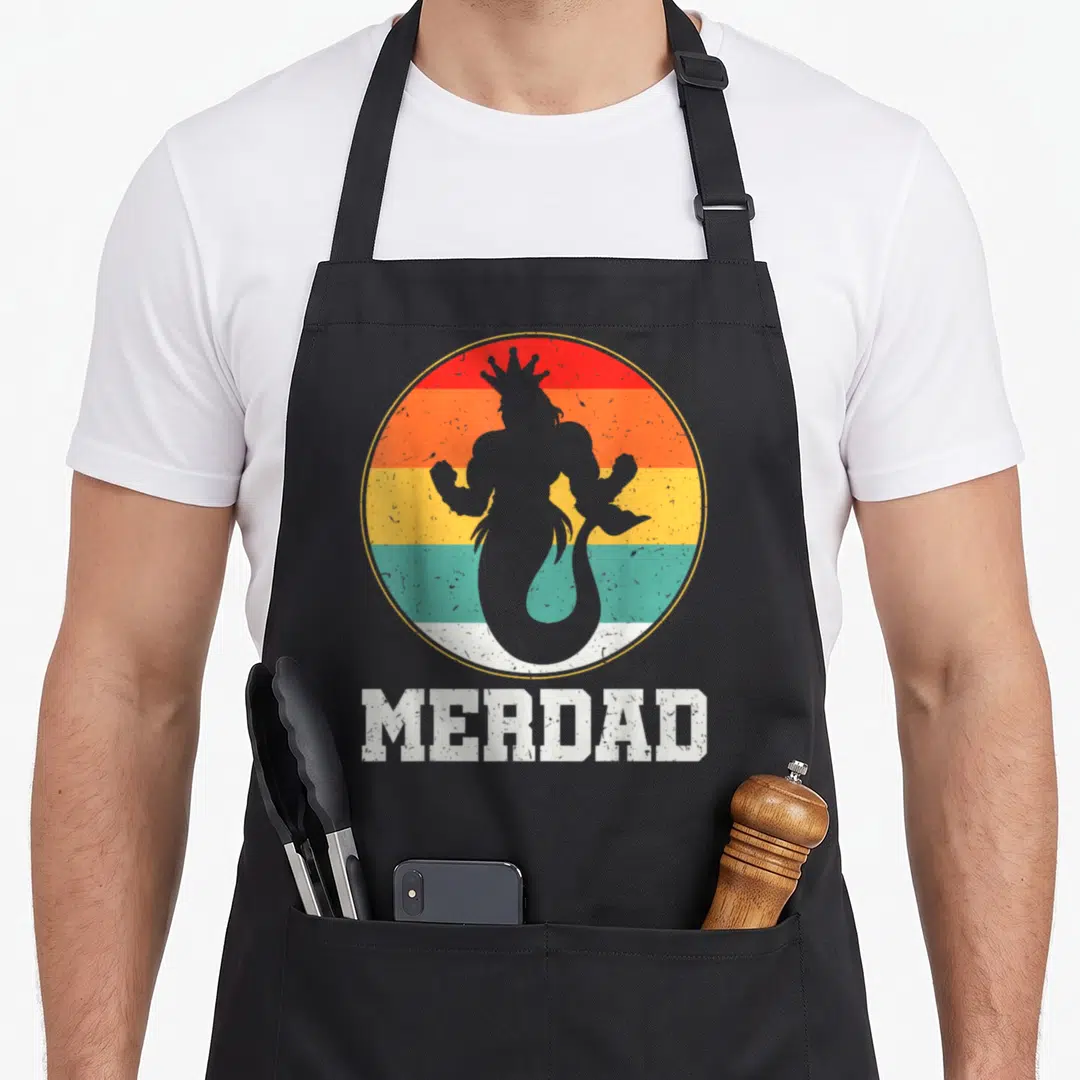 Merdad safety apron - Grey merman silhouette in red orange yellow teal striped circle with MERDAD text below — shown on a black cotton canvas apron against a white background