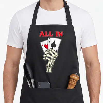Poker skeleton apron - Skeleton hand holding 7 of hearts and 2 of spades below red ALL IN text — shown on a black cotton canvas apron against a white background