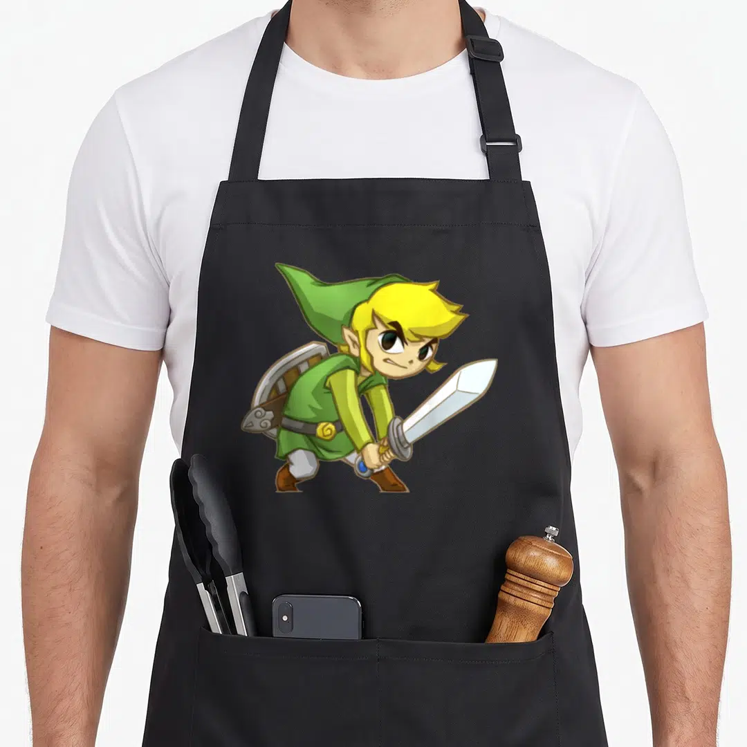 Link track apron - Cartoon elf with yellow hair holding silver sword, green tunic, brown boots, shield on back — shown on a black cotton canvas apron against a white background