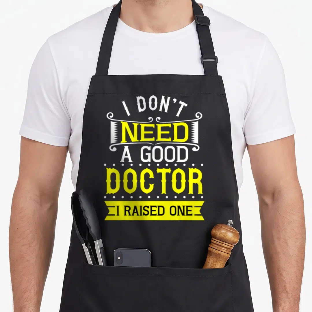 Medical doctor with apron - I don't need a good doctor I raised one text art in yellow and white — shown on a black cotton canvas apron against a white background