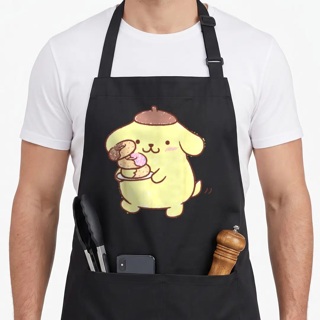 Pompompurin donut apron - Yellow cartoon dog in brown hat holding white plate with three donuts — shown on a black cotton canvas apron against a white background