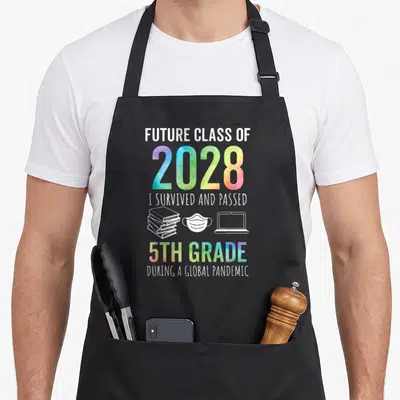 Future graduation year apron - Future Class of 2028 5th Grade Pandemic text with book mask laptop icons rainbow gradient — shown on a black cotton canvas apron against a white background