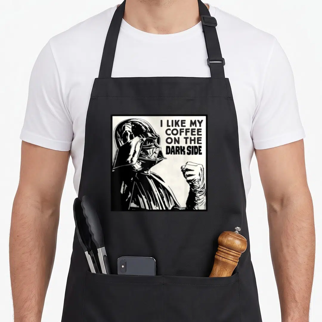 Dark coffee apron - Darth Vader line art with I LIKE MY COFFEE ON THE DARK SIDE text in black and white — shown on a black cotton canvas apron against a white background