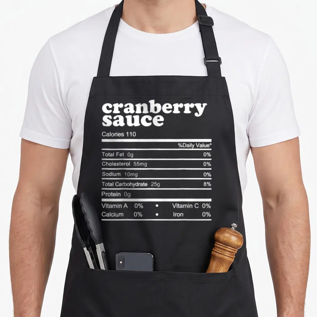 Nutrition fact thanksgiving apron - White nutrition facts label text reading cranberry sauce calories 110 and zero — shown on a black cotton canvas apron against a white background